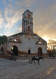 A chrome pony passes a real pony at sunrise in front of Iglesia de Santa Ana Trinidad, Cuba